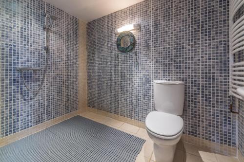a bathroom with a toilet and a shower with blue tiles at Holland House Barn in Docking