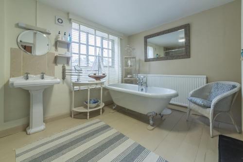 een badkamer met een bad, een wastafel en een spiegel bij Holland House 10 in Docking
