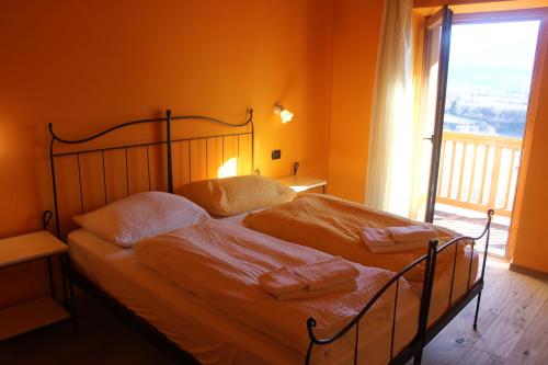 um quarto com uma cama com paredes cor de laranja e uma janela em Maso Fiorini em Rovereto