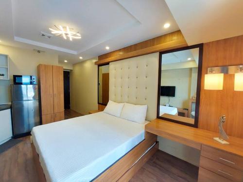 a bedroom with a large white bed and a mirror at Centrio Tower w/ Netflix + WiFi in Cagayan de Oro