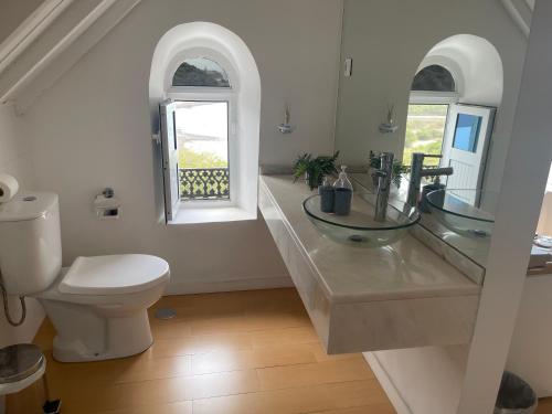 a bathroom with a toilet and a sink and a window at KAZARÃO DI MAVETE- Guesthouse in Praia