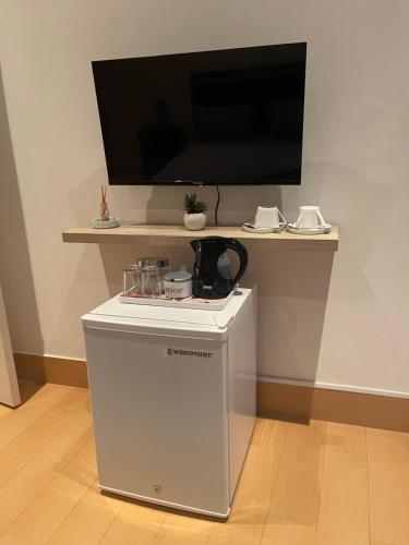 a small white refrigerator with a flat screen tv on a wall at KAZARÃO DI MAVETE- Guesthouse in Praia