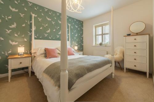 a bedroom with a four poster bed with birds on the wall at Lavandula 6 in Burnham Market