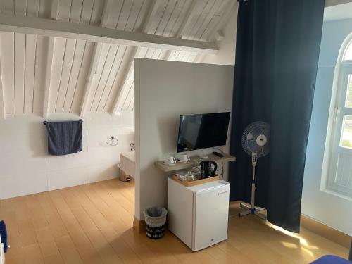 a living room with a tv and a desk with a fan at KAZARÃO DI MAVETE- Guesthouse in Praia
