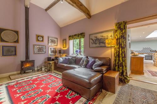 a living room with a leather couch and a fireplace at Apple Tree Barn in Langham