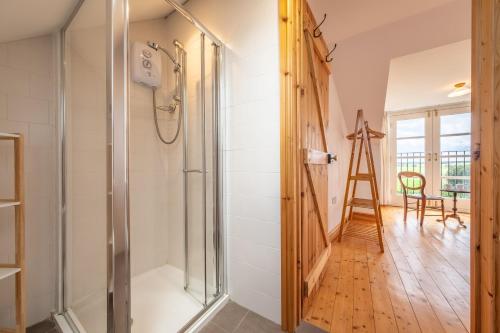 a bathroom with a shower and a wooden floor at Gallery Cottage in Wighton