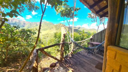 a hammock on a porch with a view of the mountains at Ecopousada Toca do Guará in Alto Paraíso de Goiás