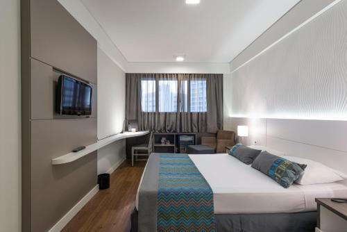 Habitación de hotel con cama y sala de estar. en Monreale Plus Midtown Campinas, en Campinas