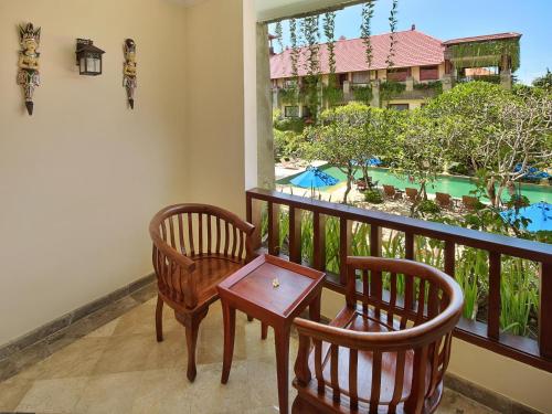 a balcony with two chairs and a table and a window at The Grand Bali Nusa Dua in Nusa Dua