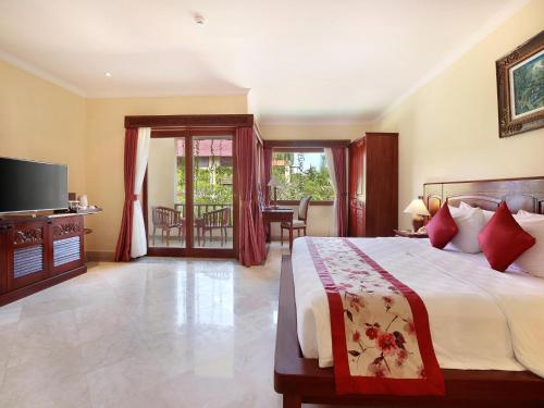 a bedroom with a large bed and a television at The Grand Bali Nusa Dua in Nusa Dua