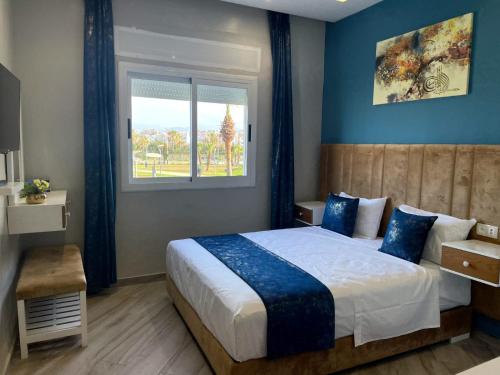 um quarto com uma cama com paredes azuis e uma janela em HOSTAL MH BORJ em Martil