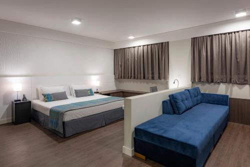 a hotel room with a bed and a couch at Monreale Plus Midtown Campinas in Campinas