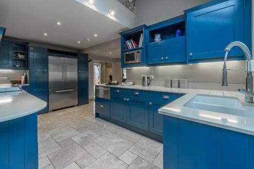 a blue kitchen with stainless steel appliances and blue cabinets at The Little House in Brancaster