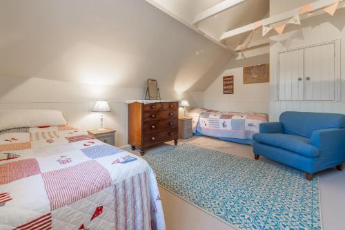 a bedroom with a bed and a blue chair at The Little House in Brancaster