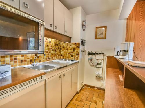 une cuisine avec des armoires blanches et un évier dans l'établissement Appartement duplex cosy pour 6-8 personnes avec parking - FR-1-685-21, aux Gets