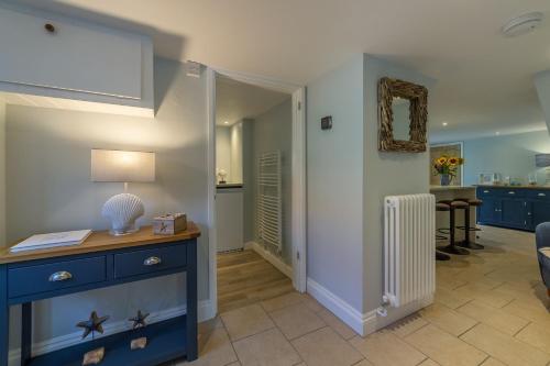 a living room with a blue dresser and a table with a lamp at Chestnut Cottage in Thornham