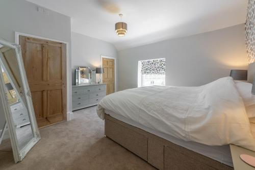 a bedroom with a bed and a dresser and a window at Chestnut Cottage in Thornham