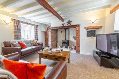 a living room with a couch and a tv at Swift Cottage in Dersingham