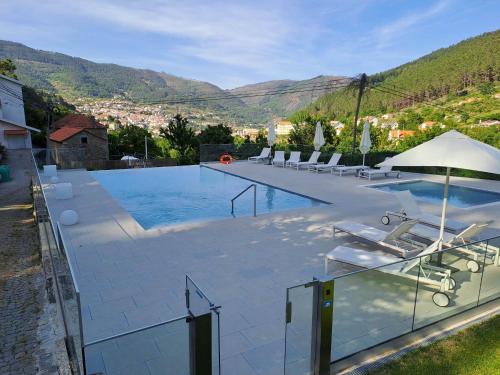 a large swimming pool with chairs and an umbrella at INATEL Manteigas in Manteigas