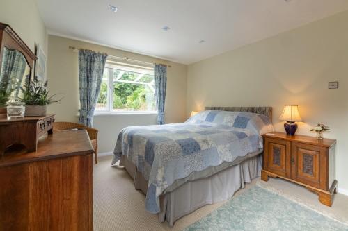 a bedroom with a bed and a dresser and a window at Bettys Cottage in Brancaster