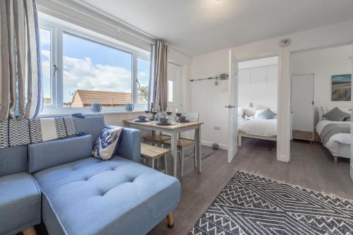 uma sala de estar com um sofá azul e um quarto em Beach Retreat em Weybourne