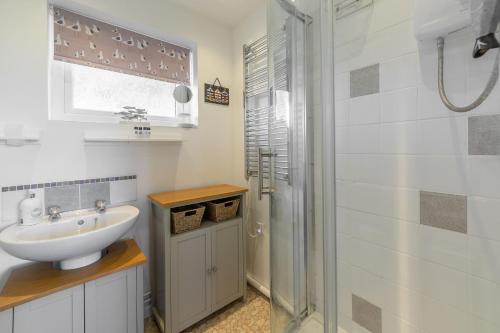 uma casa de banho branca com um lavatório e um chuveiro em Beach Retreat em Weybourne