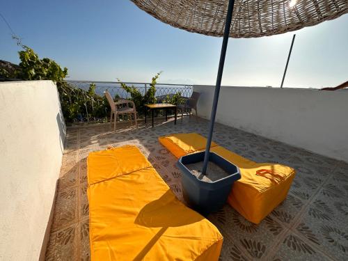 un patio con 2 tappetini gialli e un ombrello di Goknar Knidos Oasis Nature Hotel a Datça