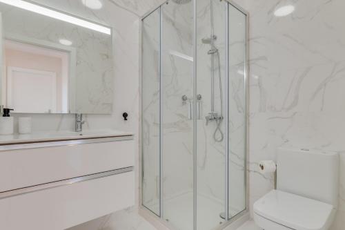 a white bathroom with a shower and a toilet at Banana Tree in Câmara de Lobos