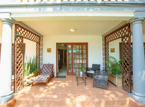 a porch of a house with a couch and chairs at Golden Candle Guest House in Roodepoort
