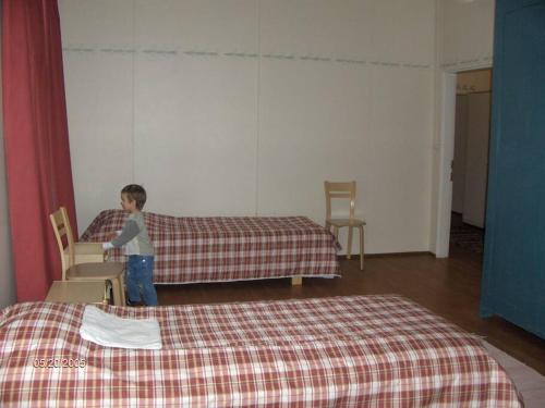 um rapaz de pé num quarto com uma cama em Maaseutumajoitus, Kesti-Iivarin Majatalo em Ylistaro