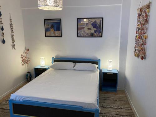 een slaapkamer met een blauw bed en 2 nachtkastjes bij Garden Apartment in Pefkochori