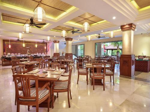 a dining room with wooden tables and chairs at The Grand Bali Nusa Dua in Nusa Dua