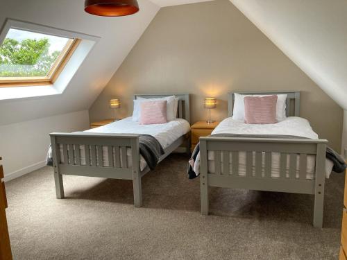 2 Betten in einem Dachzimmer mit 2 Fenstern in der Unterkunft Dalvista Cottage in Leurbost