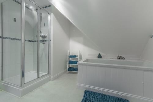 a white bathroom with a shower and a sink at The Moorings in Wells next the Sea