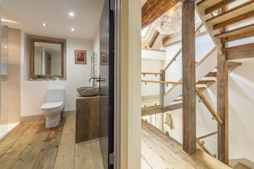 a bathroom with a toilet and a sink and a staircase at Hideaway Barn 4 in Thornham
