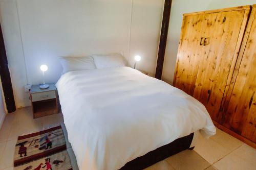 a bedroom with a large white bed with a wooden door at Golden Candle Guest House in Roodepoort