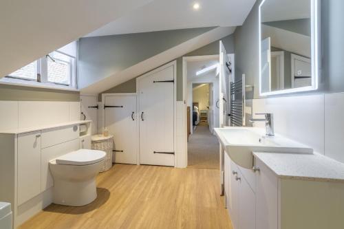 a white bathroom with a toilet and a sink at Sea Holly House in Blakeney