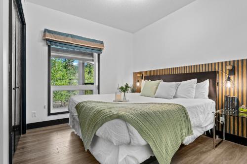 a bedroom with a large bed with a green blanket at The Mountaineer by InstantSuites Pool & HotTub in Canmore