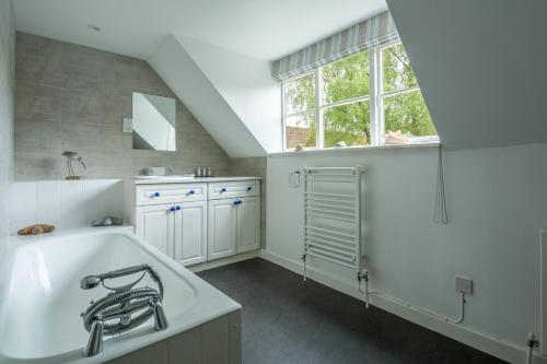 a white kitchen with a sink and a window at The Tack House in Holkham