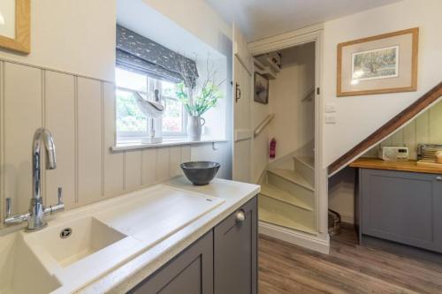 eine Küche mit einem Waschbecken und einer Treppe in der Unterkunft Piper Cottage 2 in Holme next the Sea