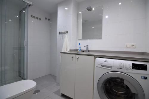 een witte badkamer met een wasmachine en een douche bij Edf. Fuentes C 2ºd - Eurosur in Nerja
