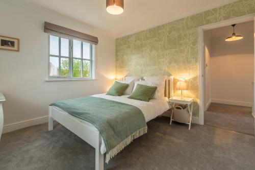 a bedroom with a bed with a green accent wall at Diggers Rest in Burnham Market