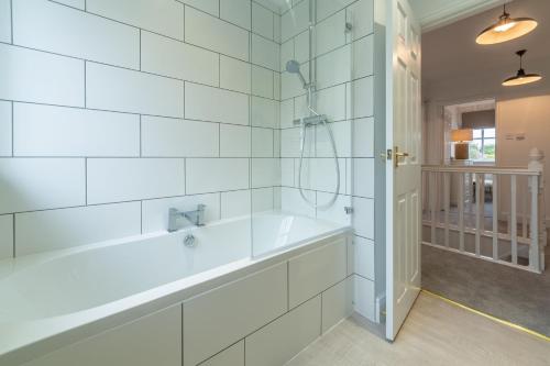 a white bathroom with a tub and a shower at Diggers Rest in Burnham Market
