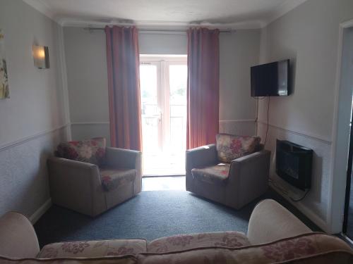 a living room with two chairs and a television at Coasters Holiday Apartments in Skegness