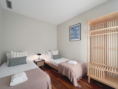 two beds in a room with white walls and wooden floors at Stay U-nique Apartments Sants II in Barcelona