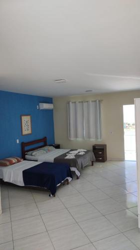 a bedroom with two beds and a blue wall at pousada costa do meio in Saquarema