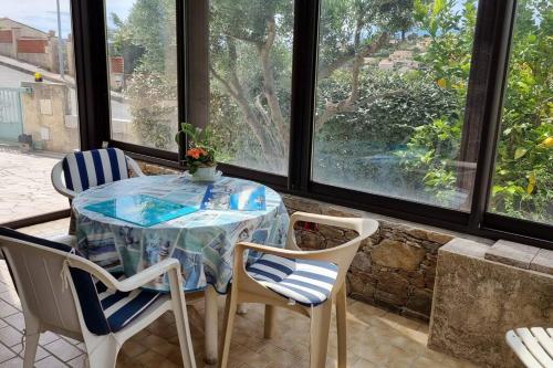 une table et des chaises dans une pièce avec des fenêtres dans l'établissement maison rez de jardin 2 à 4 personnes, au Lavandou