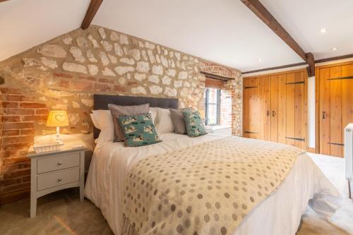 um quarto com uma cama e uma parede de tijolos em Old Smithy em Titchwell