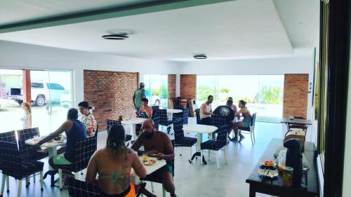 a group of people sitting at tables in a restaurant at pousada costa do meio in Saquarema