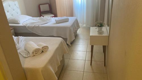 a hotel room with two beds and a table with towels at Nese Hotel in Cesme